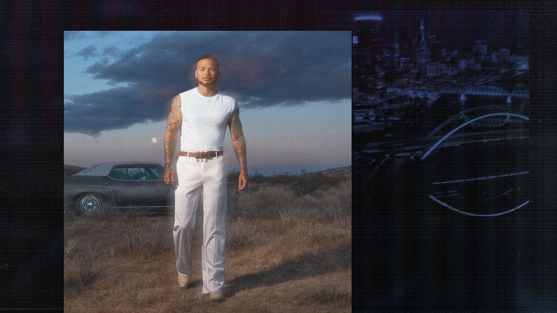 A man in white clothing stands in a grassy field at dusk, with a classic car in the background and a cityscape to the right.