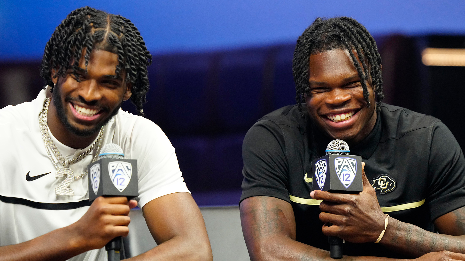 Shedeur Sanders and Travis Hunter holding microphones.