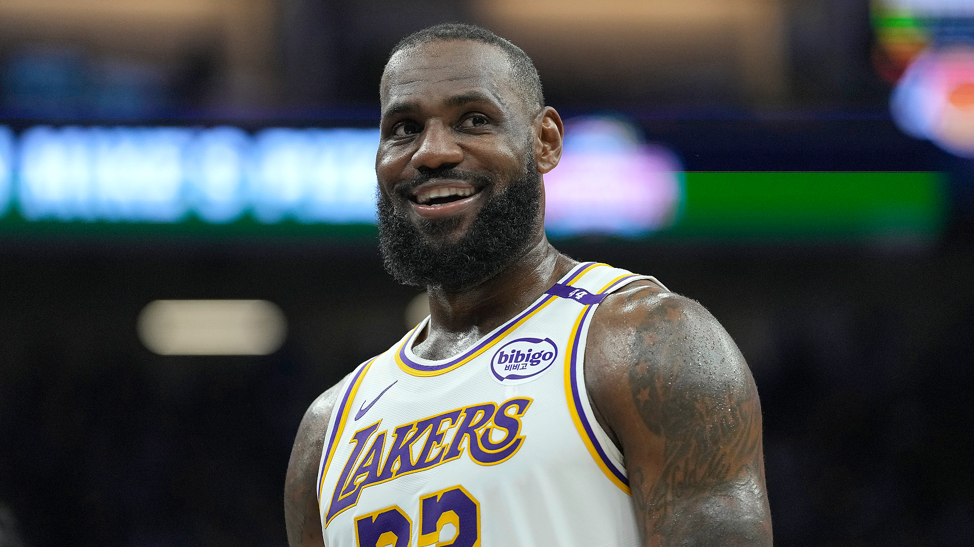 LeBron James, wearing a Los Angeles Lakers jersey, smiles on a basketball court.