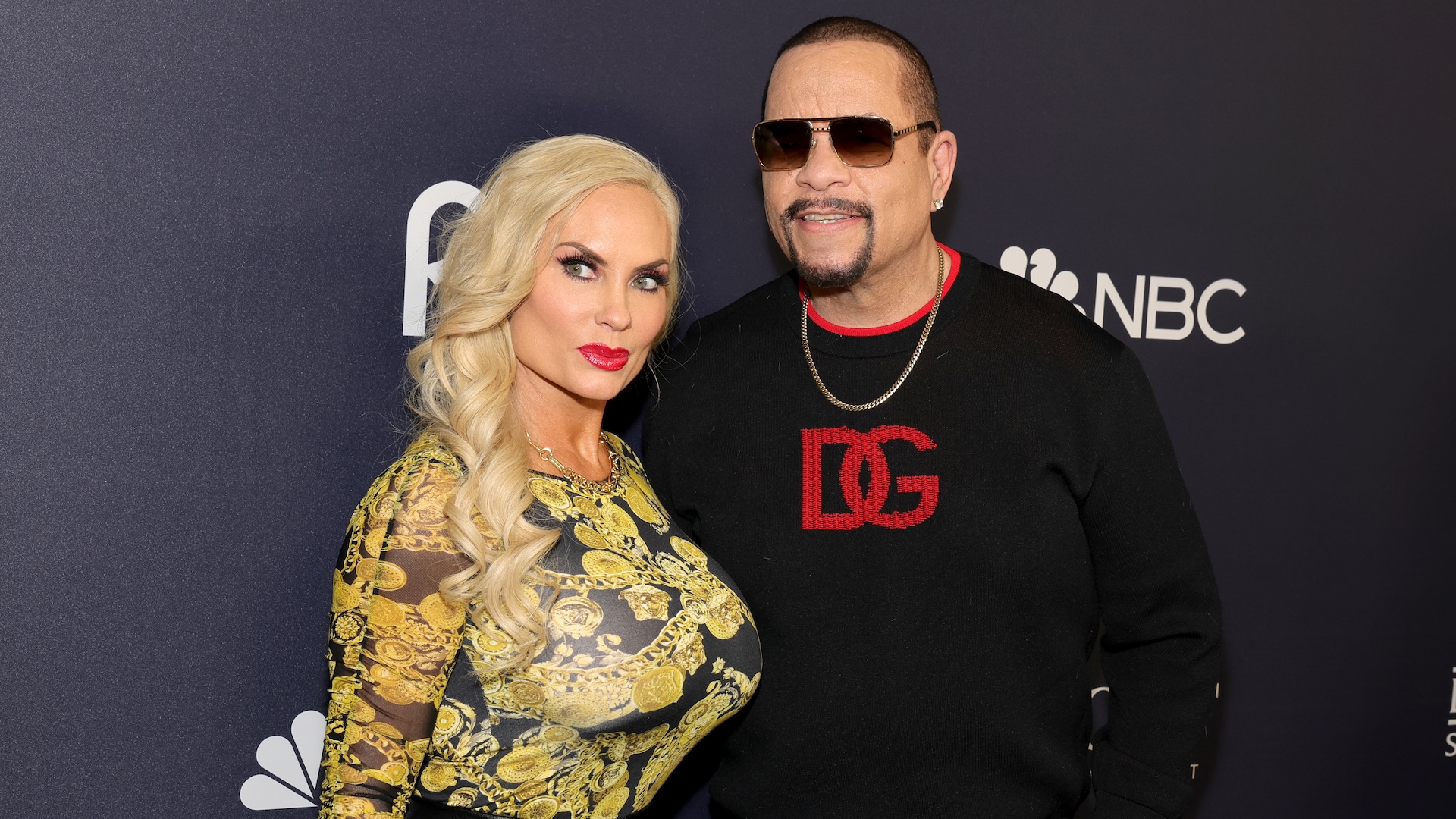 Coco Austin and Ice-T at an NBC event. Coco wears a patterned dress, and Ice-T wears sunglasses and a black sweater.