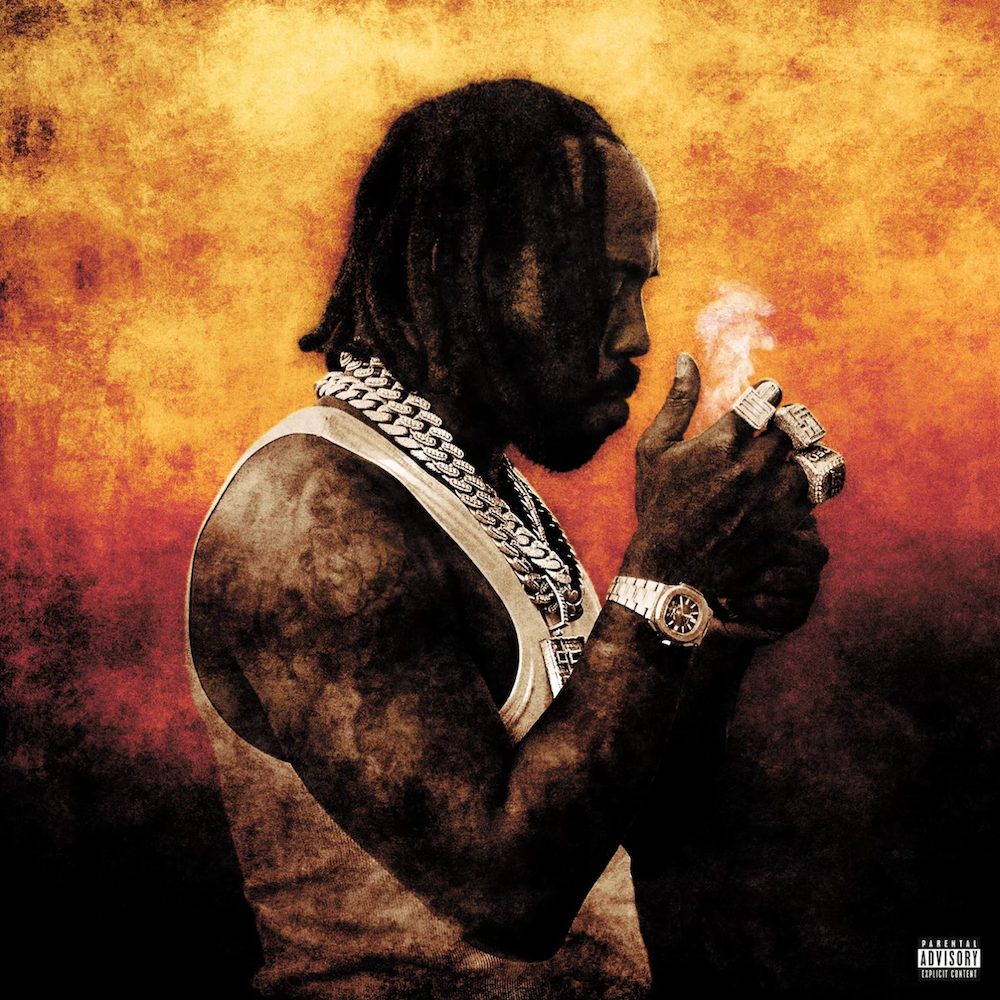 A man with dreadlocks and jewelry lights a cigarette against a fiery background.