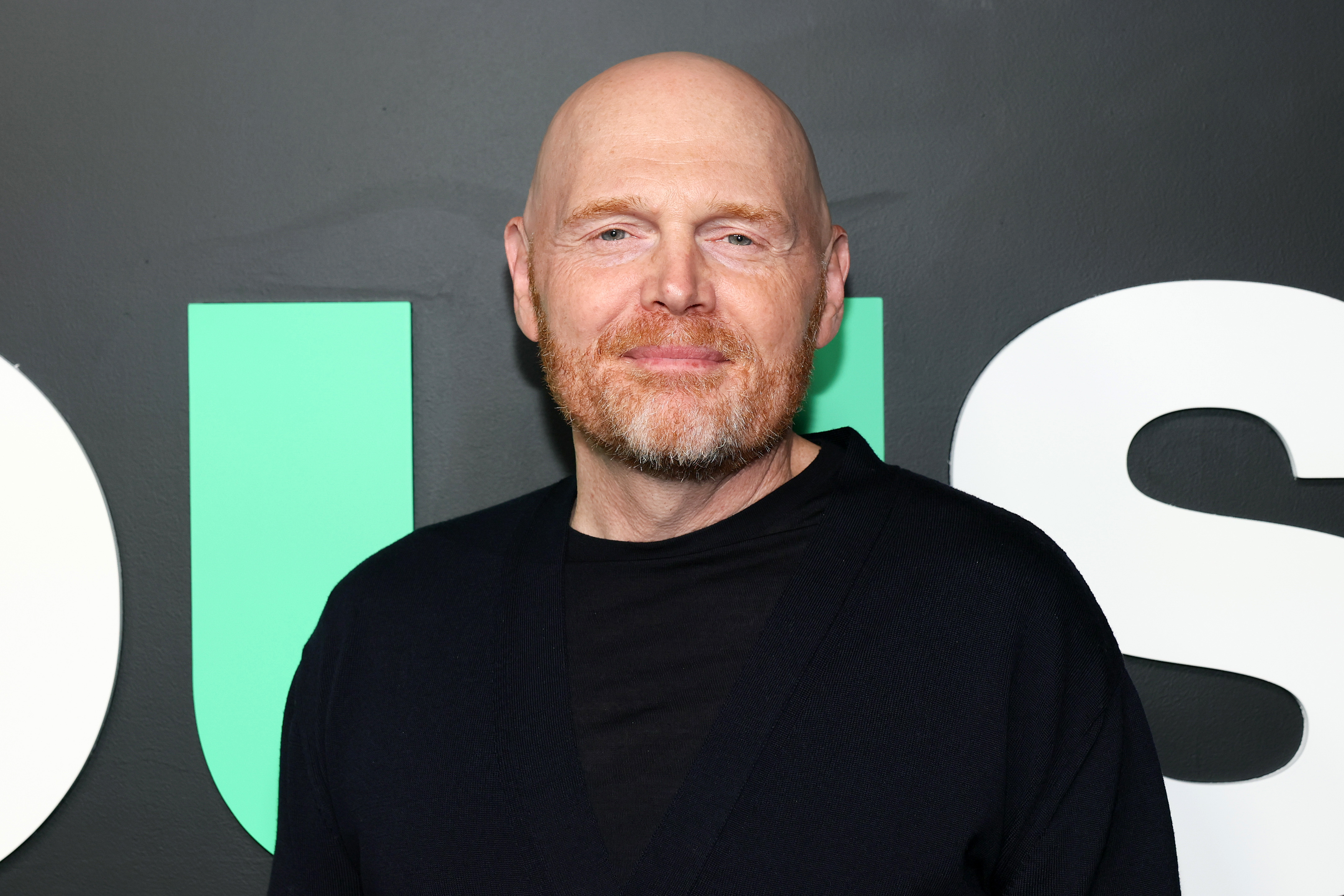 Bill Burr, wearing a black shirt, stands against a dark background with large letters.