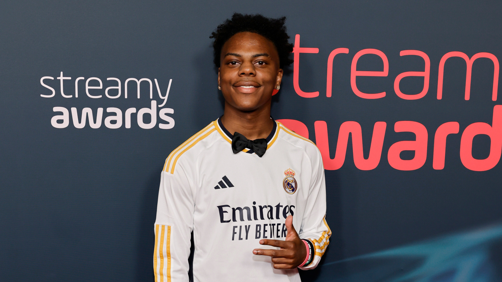 A person wearing a Real Madrid jersey and a bow tie poses at the Streamy Awards.