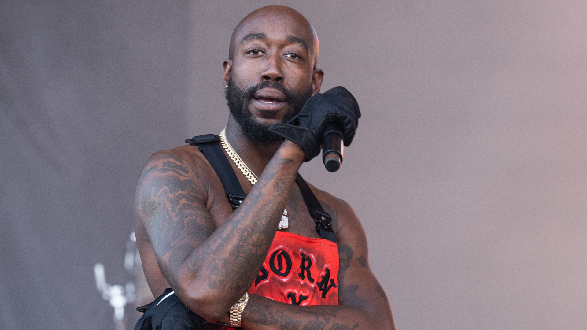 Freddie Gibbs performs on stage with a mic in his hand.