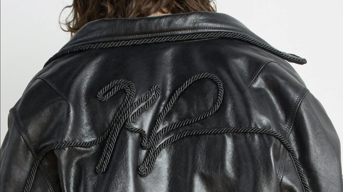 Back of a black leather jacket with intricate rope-like embroidery forming the letters "KP."