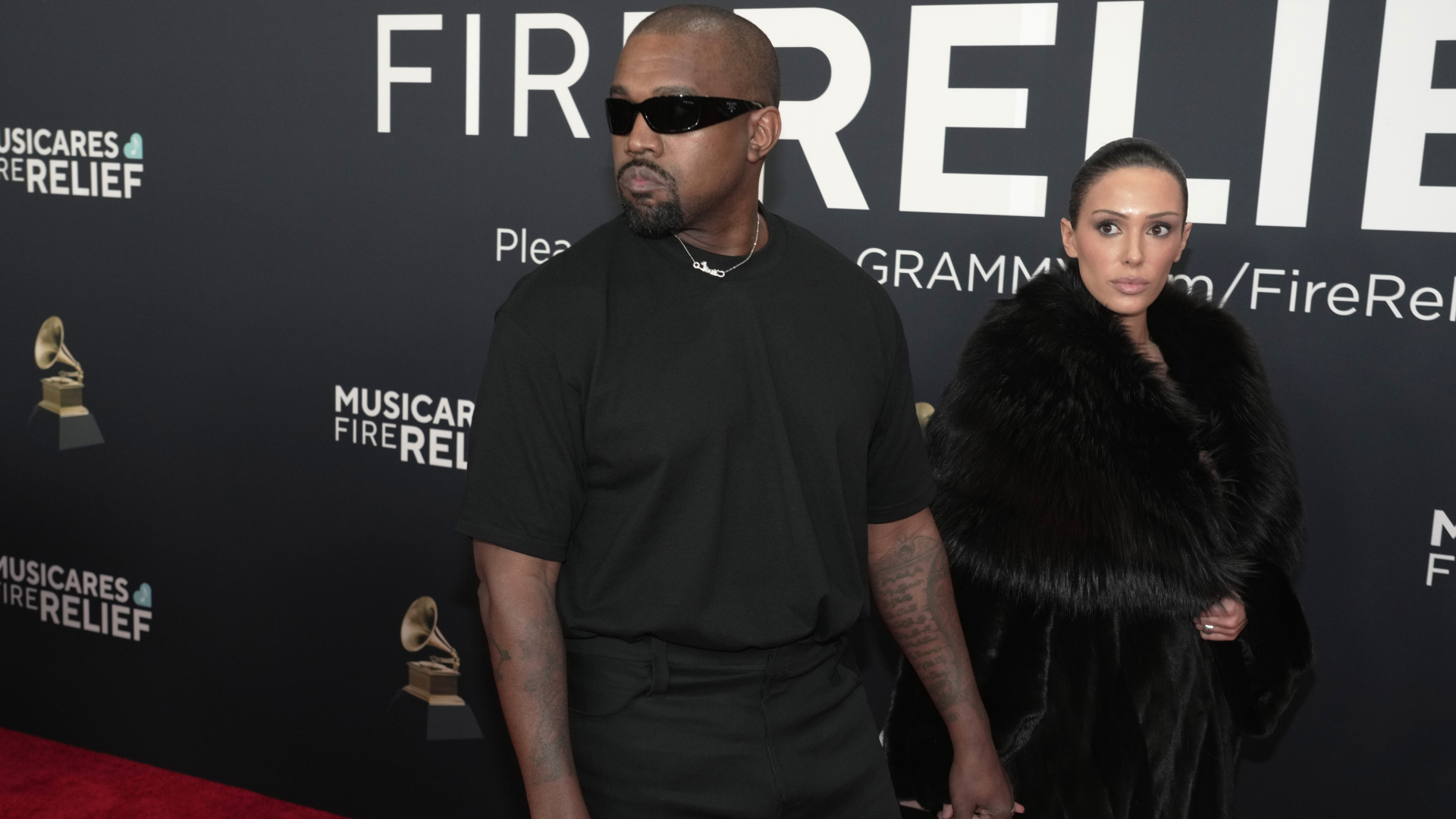 Ye in black sunglasses and Bianca in a fur coat at a MusiCares event.