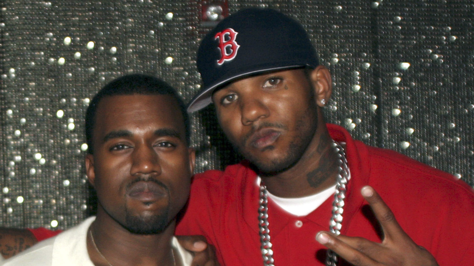 Kanye West and The Game pose together; Kanye in a white shirt, The Game in a red shirt and Boston cap.