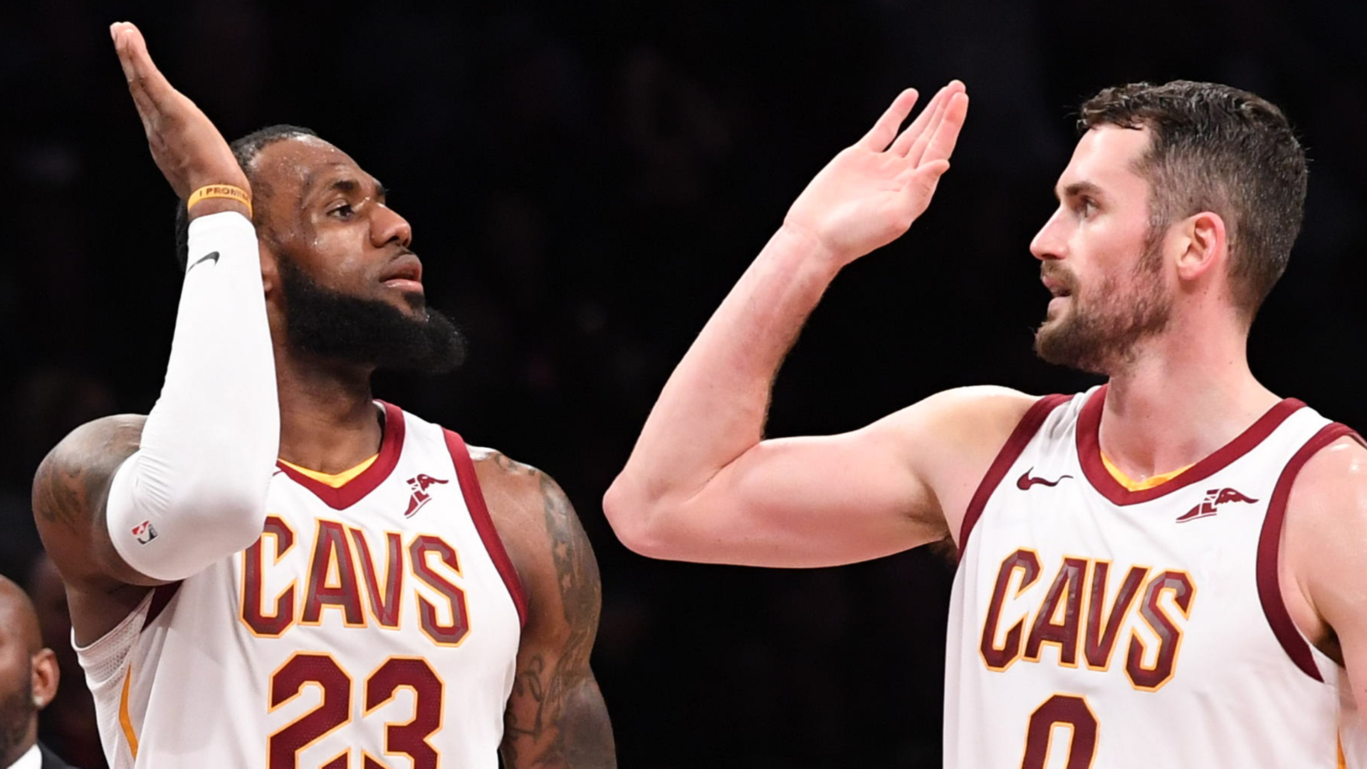 LeBron James and Kevin Love of the Cleveland Cavaliers high-five during a game, both wearing their team jerseys.