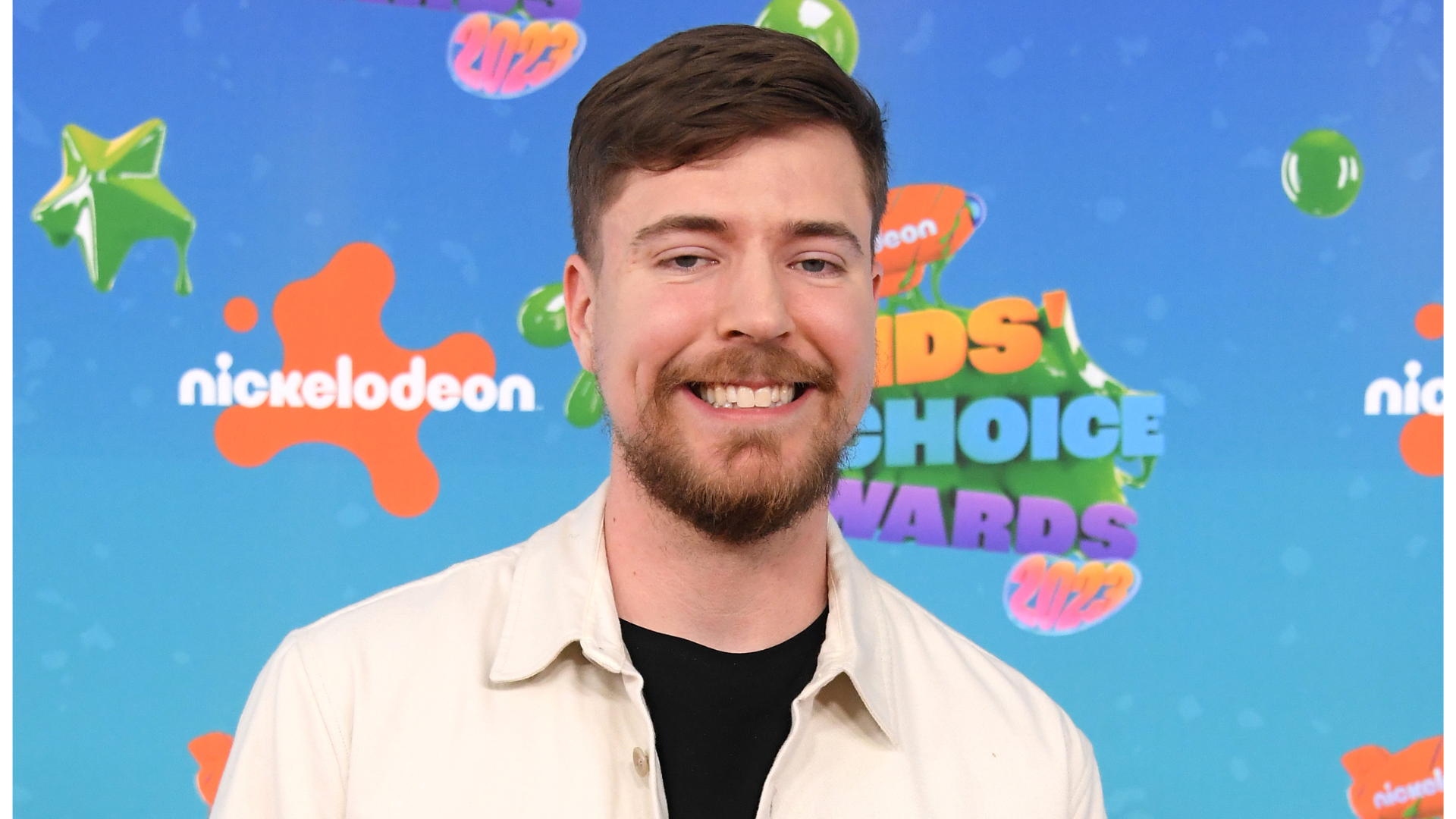 MrBeast at the Nickelodeon Kids' Choice Awards 2023, smiling in front of a colorful background with event logos.
