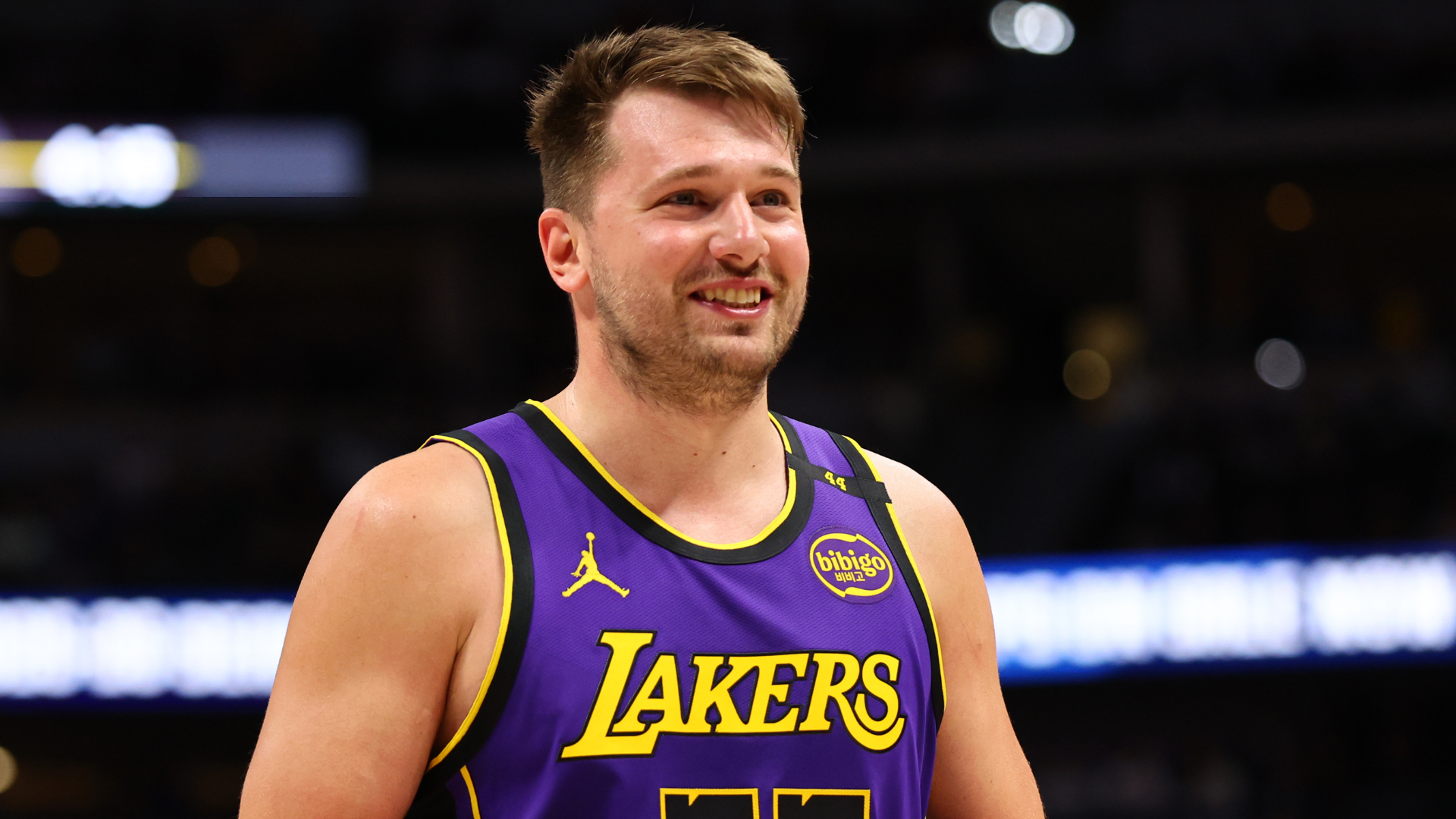 A basketball player wearing a Los Angeles Lakers jersey on the court, smiling.