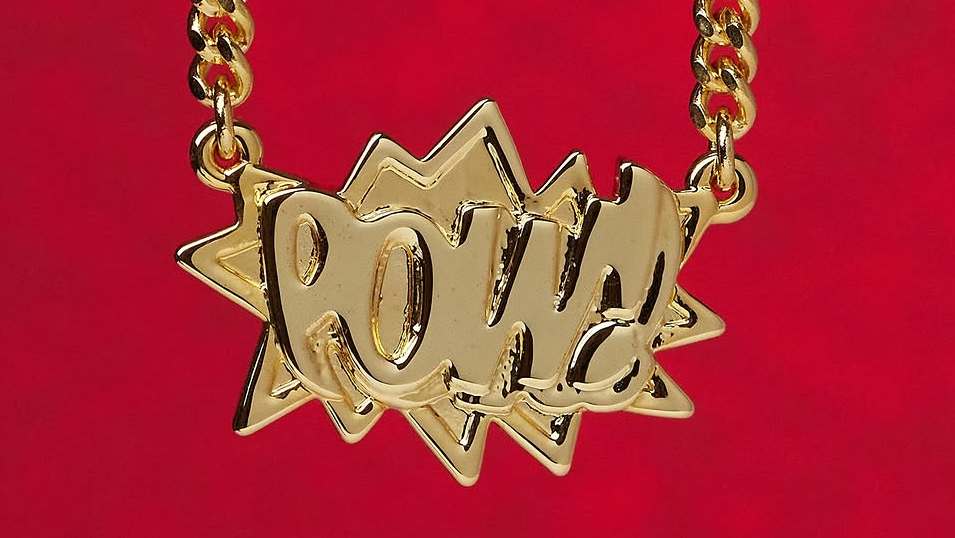 A gold necklace with a pendant spelling "POWER" in bold, stylized letters against a red background.