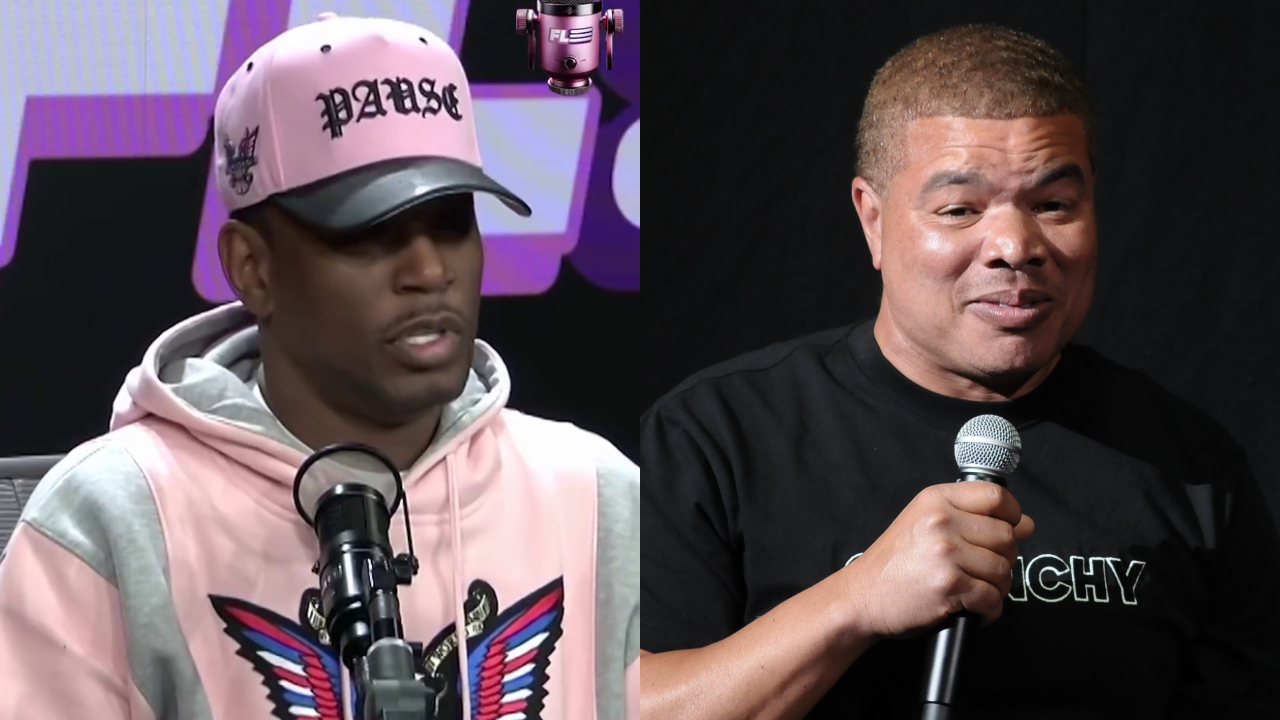 Two men are speaking into microphones. Cam'ron on the left wears a pink hat and hoodie. Comedian Red Grant on the right wears a black shirt, smiling while holding a mic.