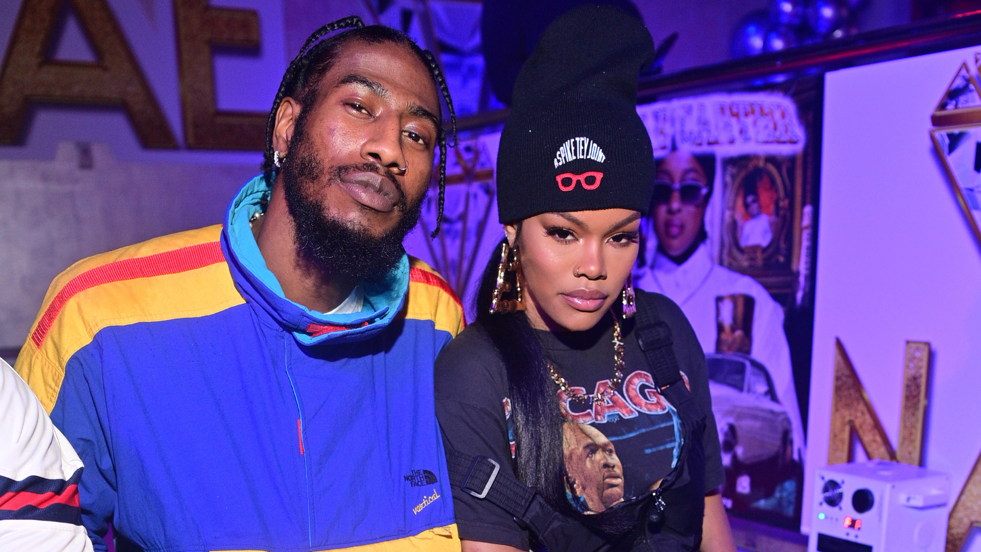 Iman Shumpert and Teyana Taylor pose together at an event, with vibrant clothing and a stylish backdrop.