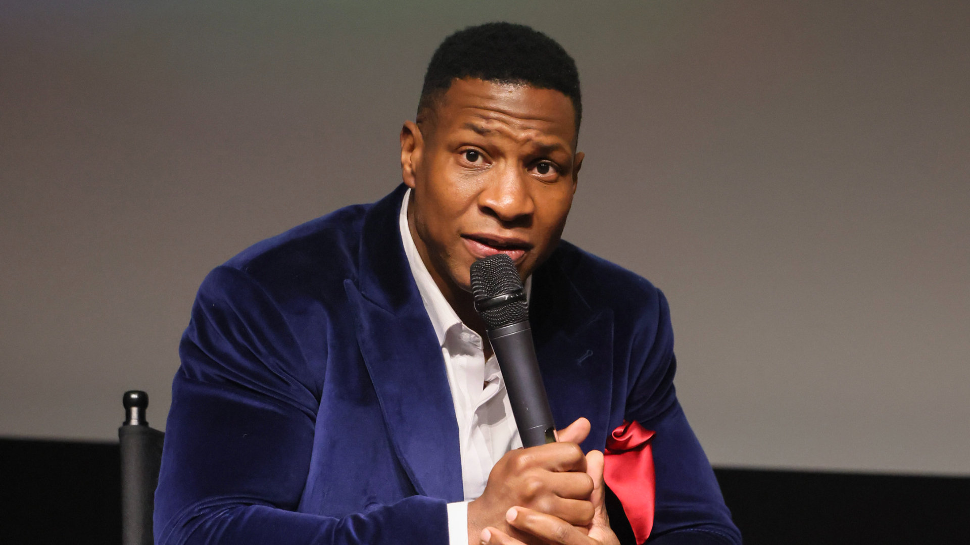 Jonathan Majors speaks into a microphone on stage.