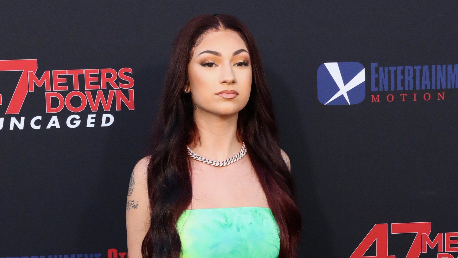 A woman with long dark hair and a green dress poses at the "47 Meters Down: Uncaged" premiere.