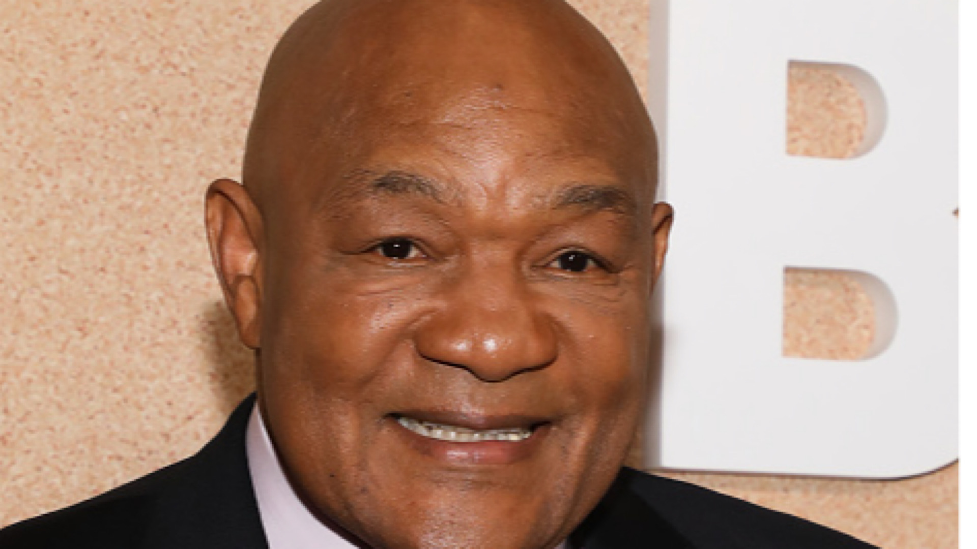 George Foreman smiling, wearing a suit.