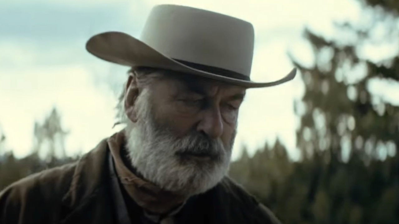 Alec Baldwin portrays an older man with a beard, wearing a wide-brimmed hat and a brown jacket, in the first trailer for 'Rust.'