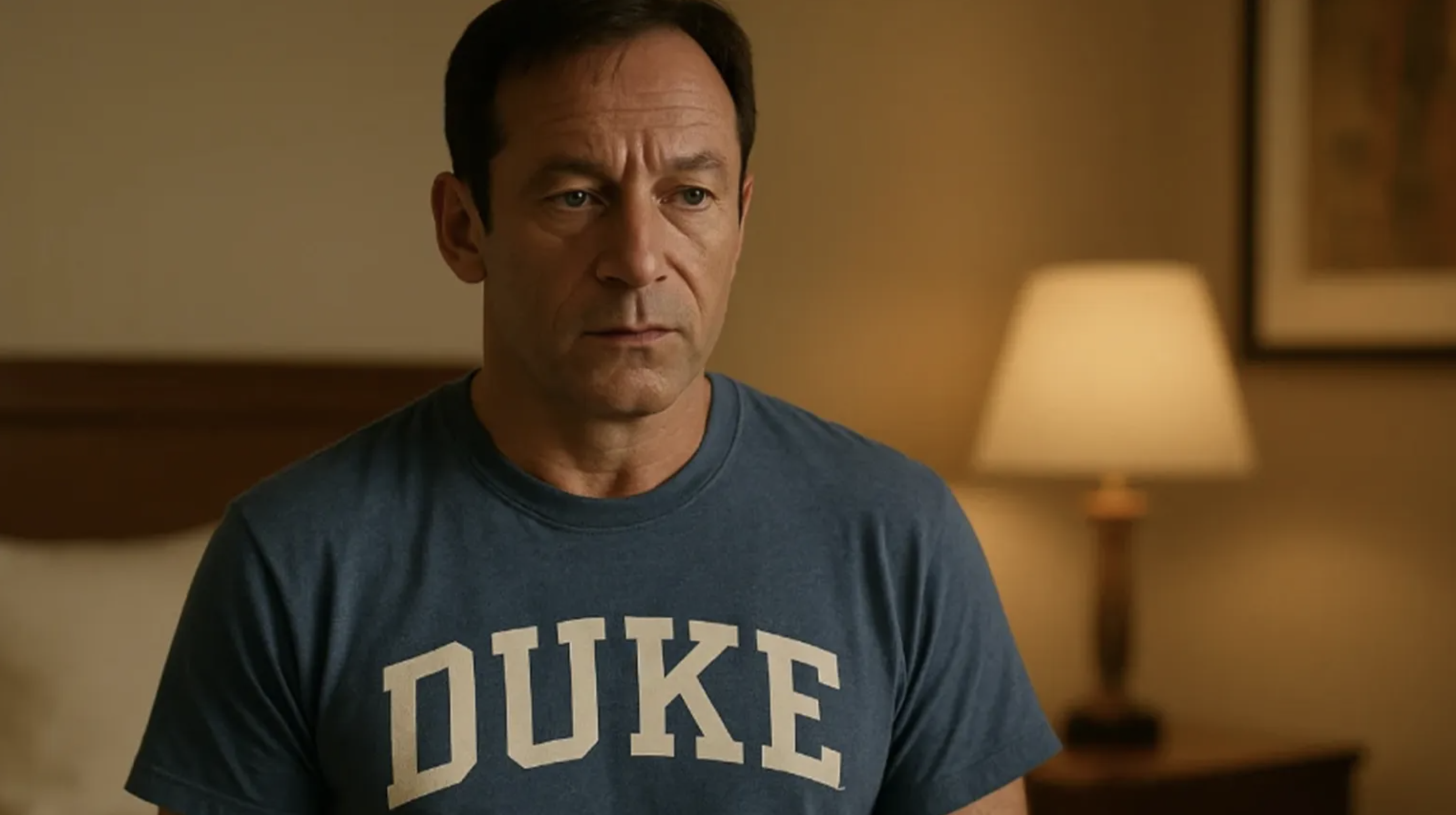 Jason Isaacs wearing a blue T-shirt with the word Duke in 'The White Lotus.'