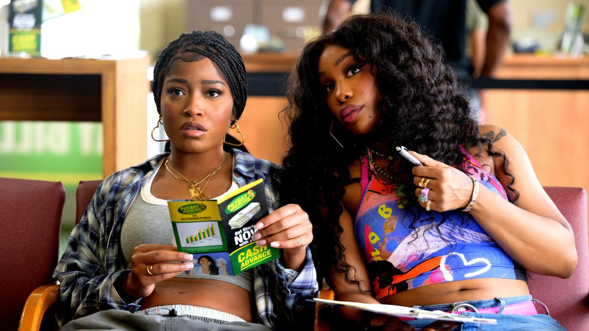 SZA and Keke Palmer sitting in a waiting area, one reading a pamphlet. Both have casual outfits and focused expressions.