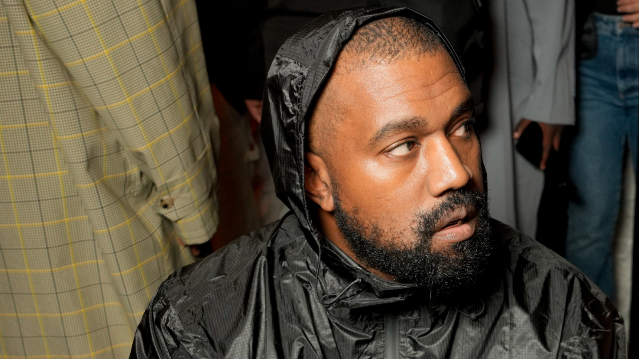 Kanye West in a black hooded jacket, looking to the side.