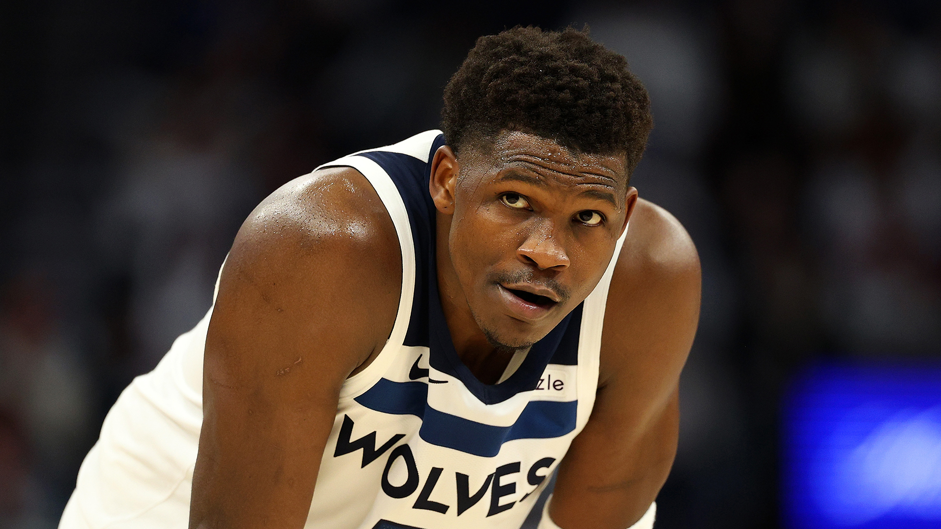 Anthony Edwards in a Timberwolves jersey is leaning forward, focused during a game.
