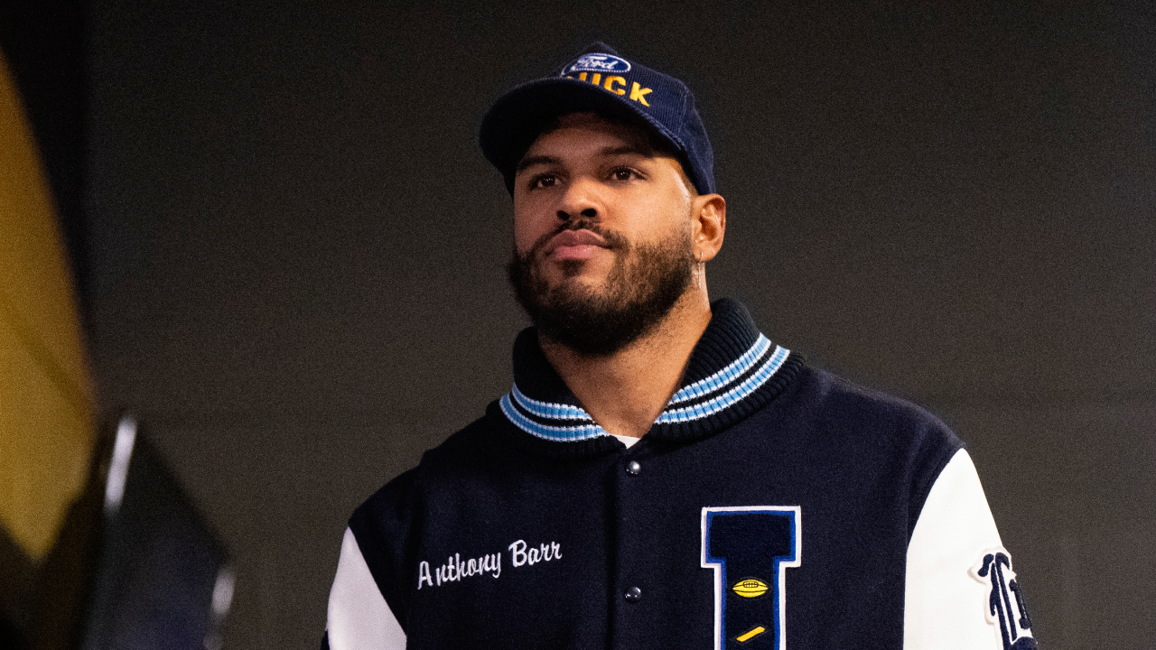 Anthony Barr wearing a varsity jacket walks through a hallway with "SKOL VIKINGS" on the wall.