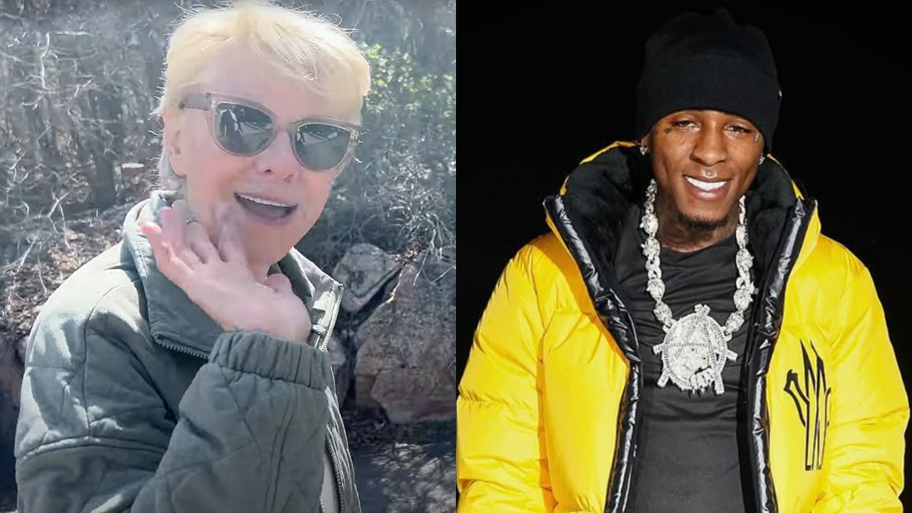 Two people side by side: on the left, an older woman with sunglasses waving; on the right, a man in a yellow jacket with a large necklace.