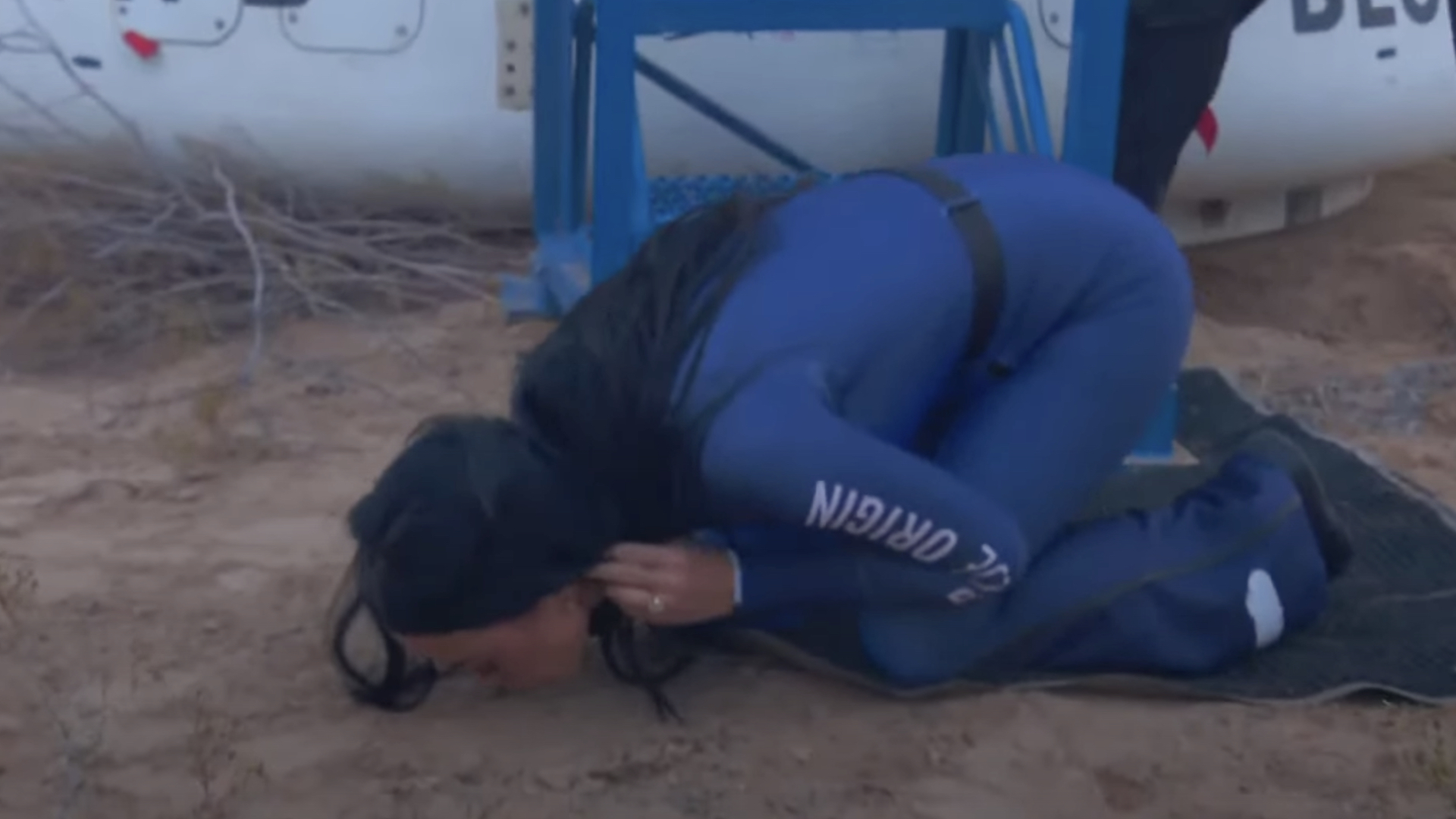 Katy Perry in blue space suit kissing ground