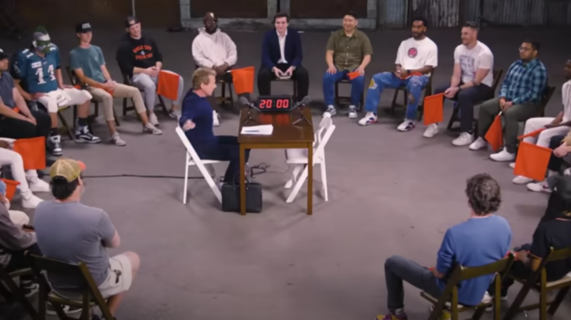A group of people sitting in a circle around a table with a timer, engaged in a discussion or meeting.