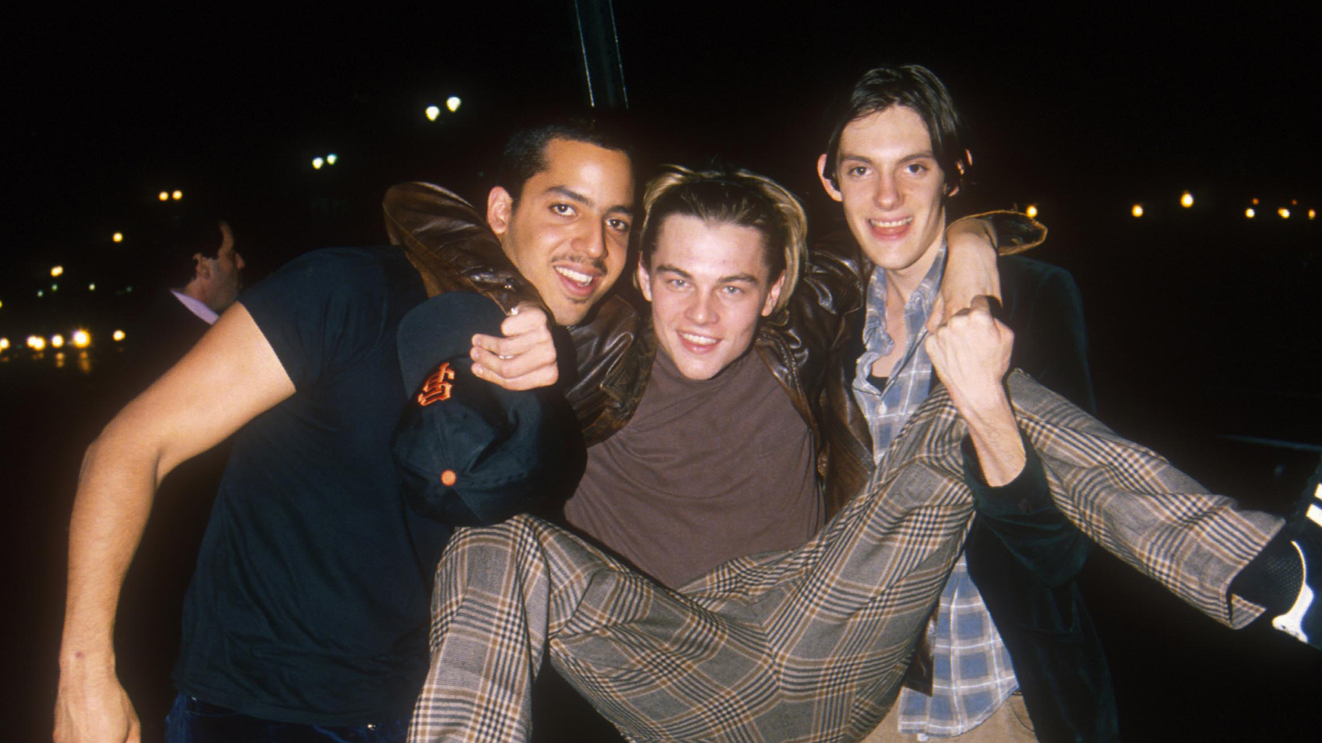 David Blaine, Leonardo DiCaprio, and Lukas Haas having fun at night, with DiCaprio being lifted by Blaine and Haas.