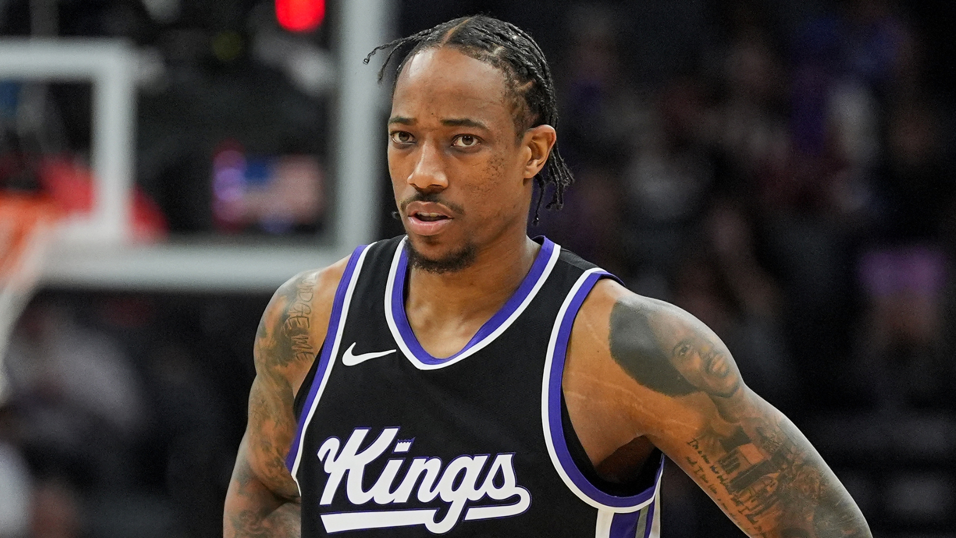 Basketball player in a Sacramento Kings jersey on the court, with visible tattoos and braided hair.