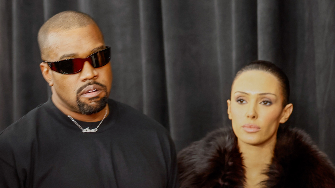 Kanye West in all black stands beside Bianca Censori