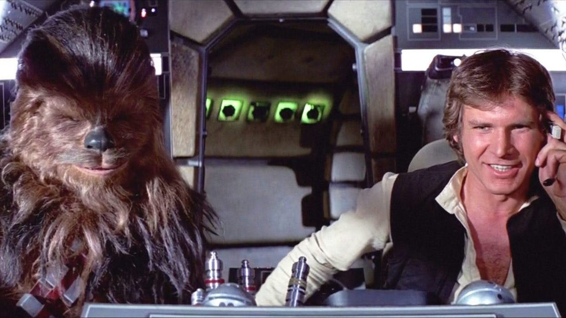 Chewbacca and Harrison Ford as Han Solo in the Millennium Falcon cockpit from Star Wars, smiling and in action.