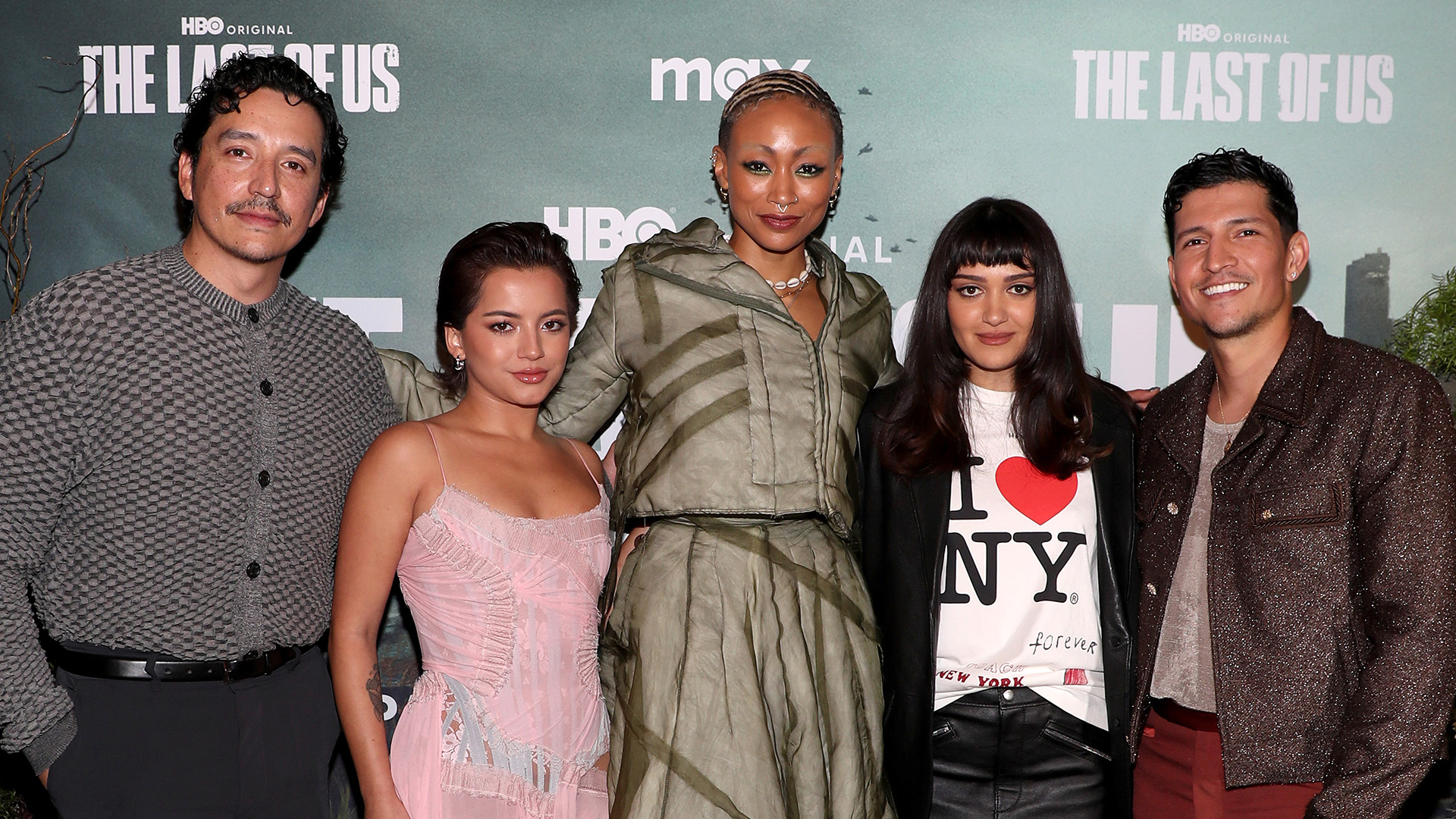 A group of five people posing at an event for "The Last of Us." They are standing in front of a backdrop with the show's title.