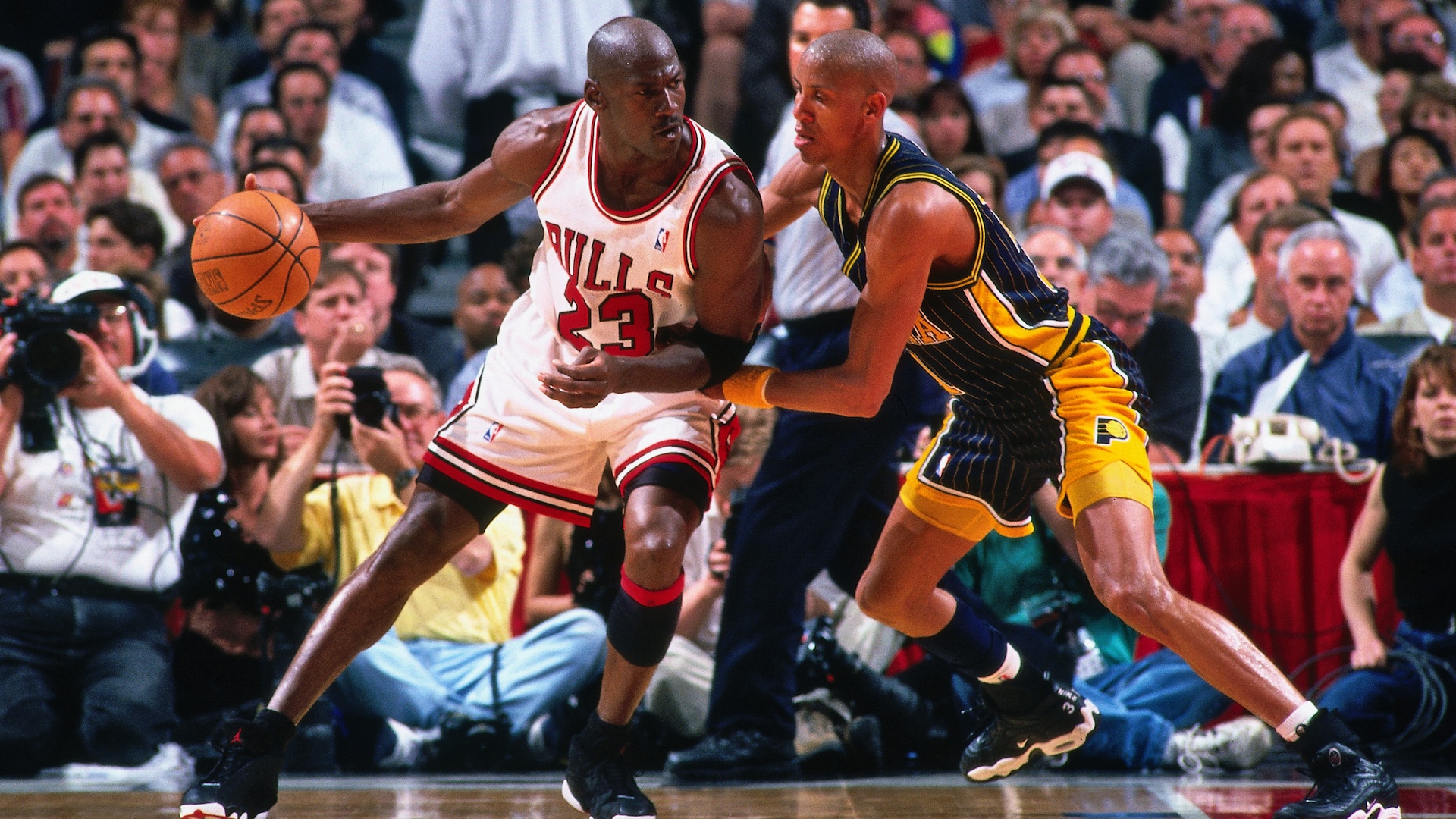 Michael Jordan in a Chicago Bulls jersey dribbles against Reggie Miller of the Indiana Pacers during a basketball game.