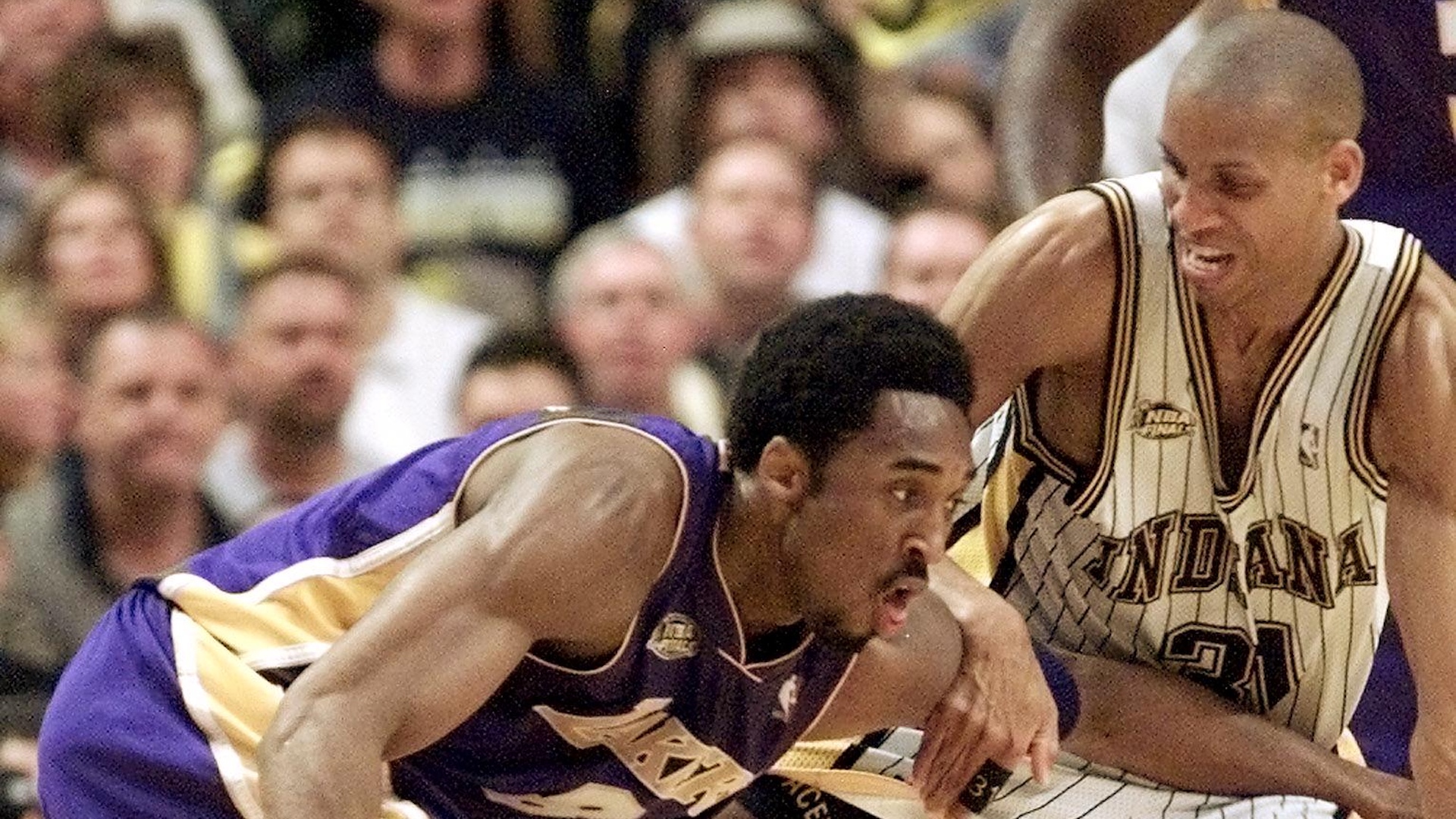 Kobe Bryant in a Lakers jersey dribbles past Reggie Miller in an Indiana Pacers jersey during a basketball game.