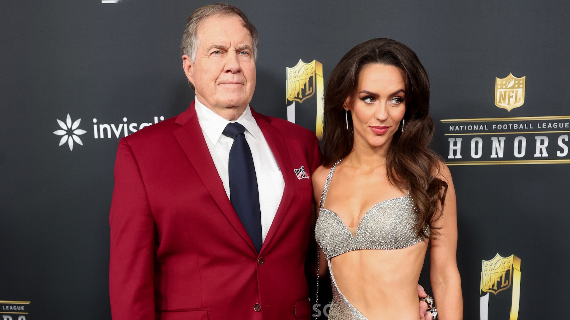 Bill Belichick in a red suit and Jordon Hudson in a glittery dress at the NFL Honors event.
