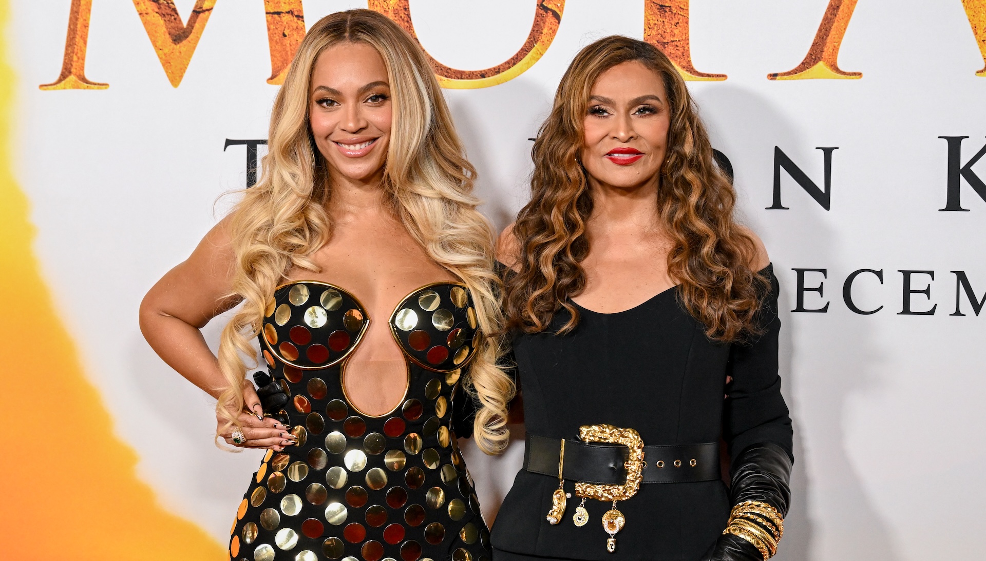 Beyoncé, in a black and gold dress, poses with her mother, Tina Knowles, in a black outfit at an event.