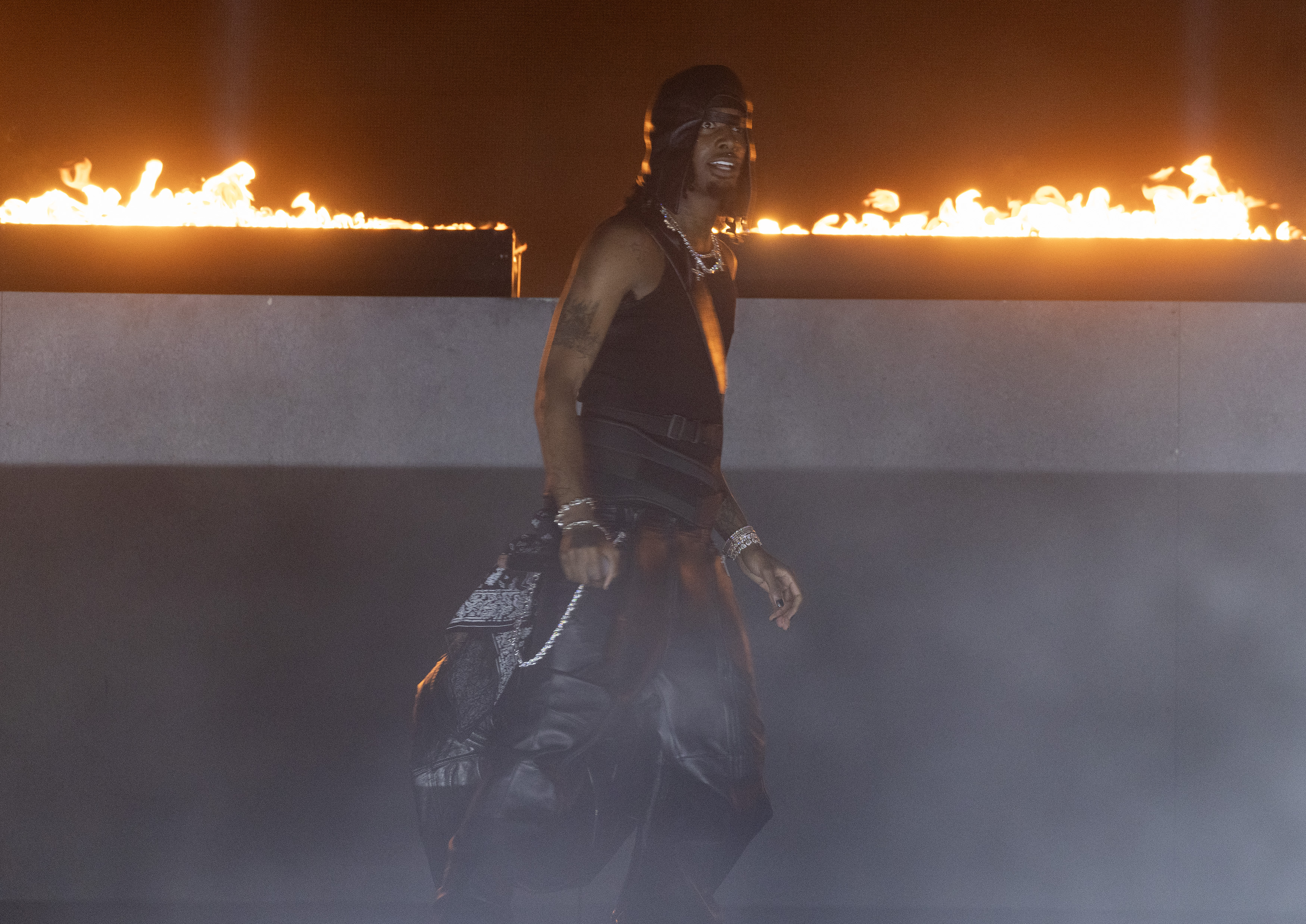Playboi Carti wearing all black in front of fire