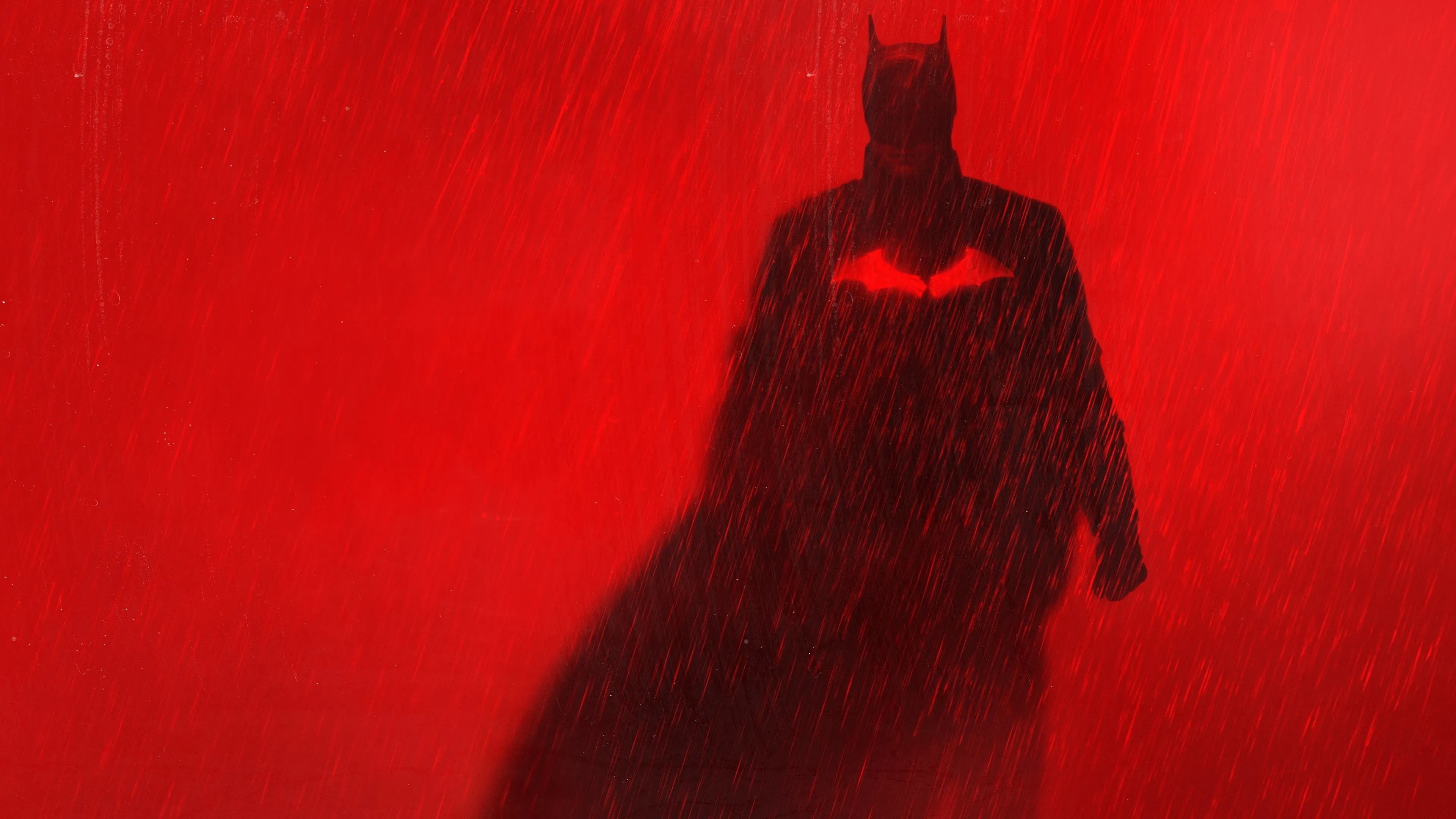 Silhouette of Batman against a red, rainy background.