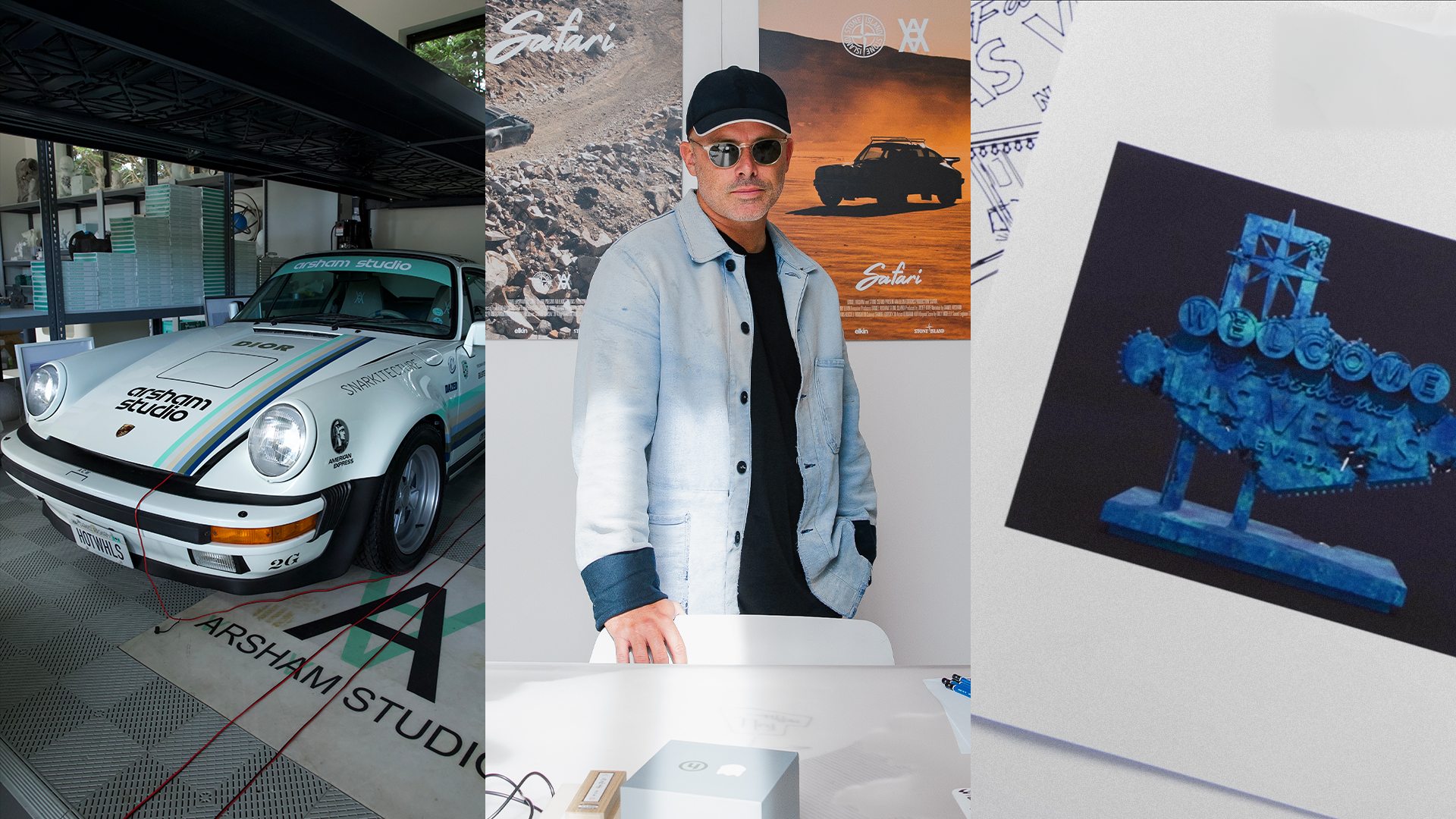 A man in a denim jacket stands beside a vintage car in a studio. Posters and art are displayed around him.