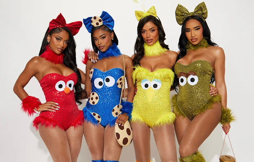 Four women in colorful, glittery costumes resembling Sesame Street characters, each with matching headbands and furry accents.
