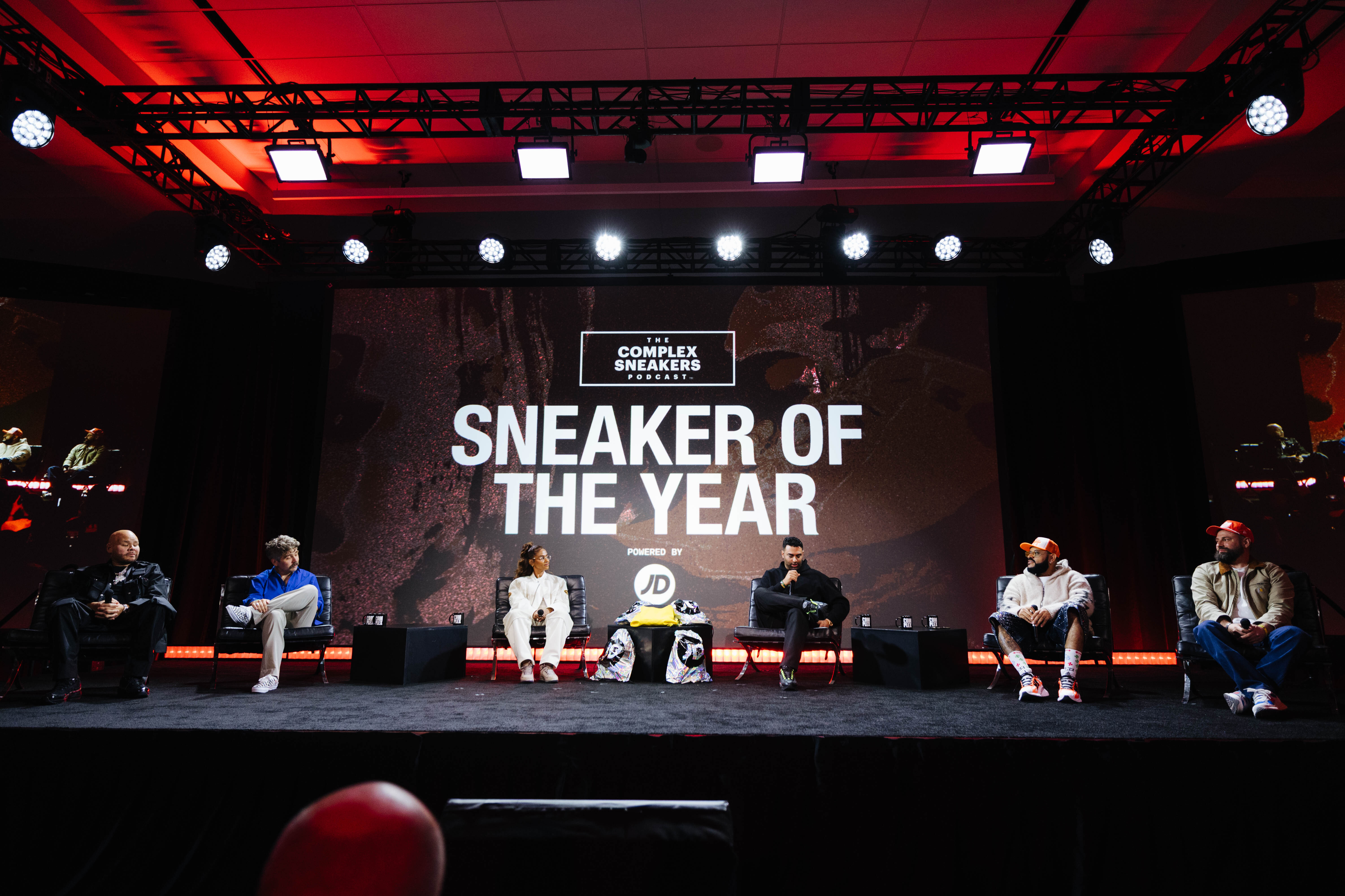 A panel of six people sit on stage at the "Complex Sneakers Sneaker of the Year" event. The backdrop displays the event name.