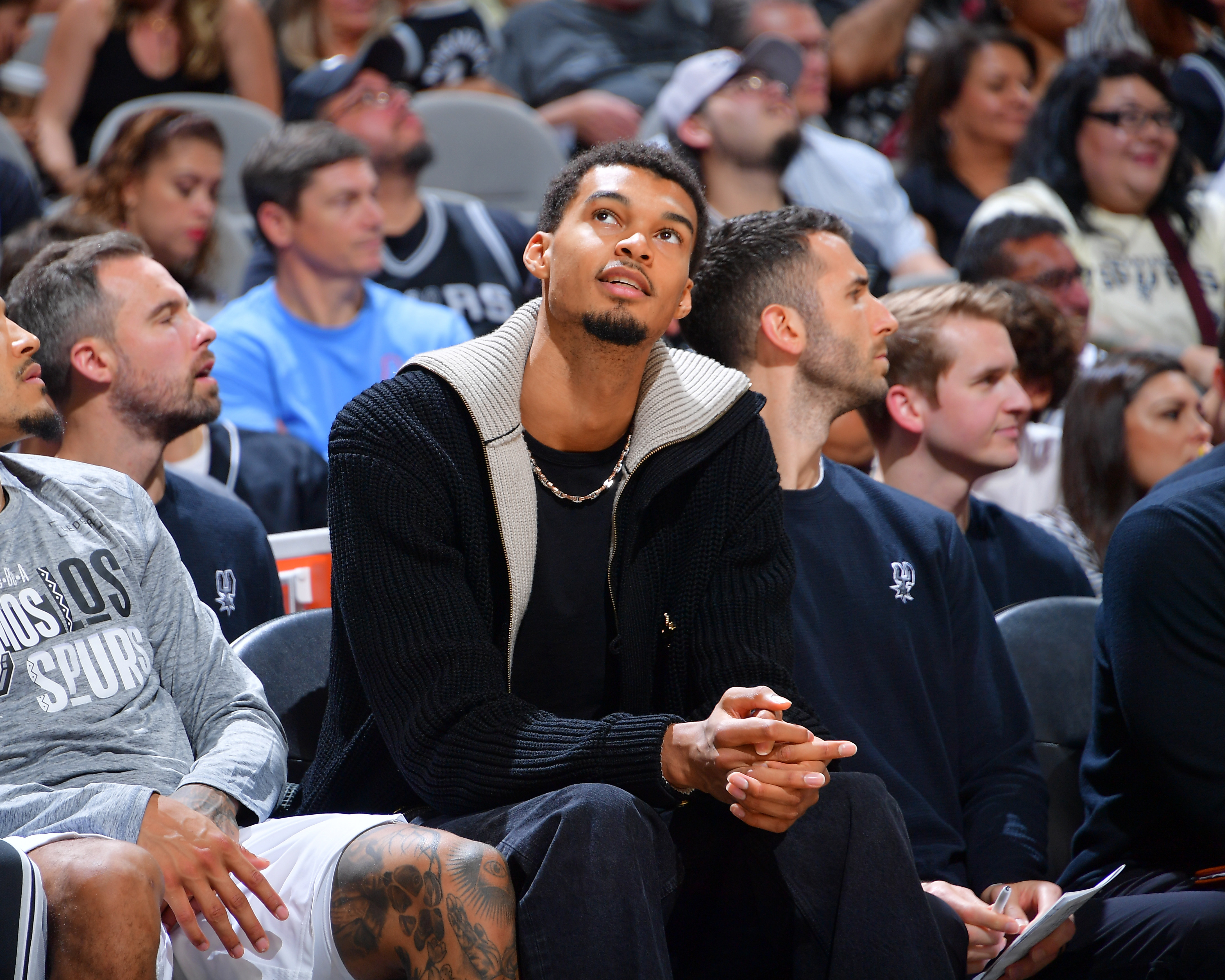Victor Wembanyama watches the Spurs-Grizzlies game from the bench.