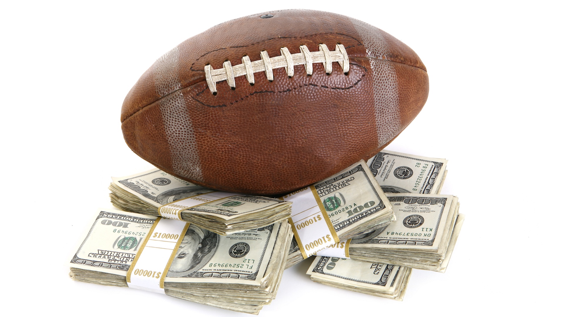 A football resting on stacks of hundred-dollar bills, symbolizing sports and wealth.