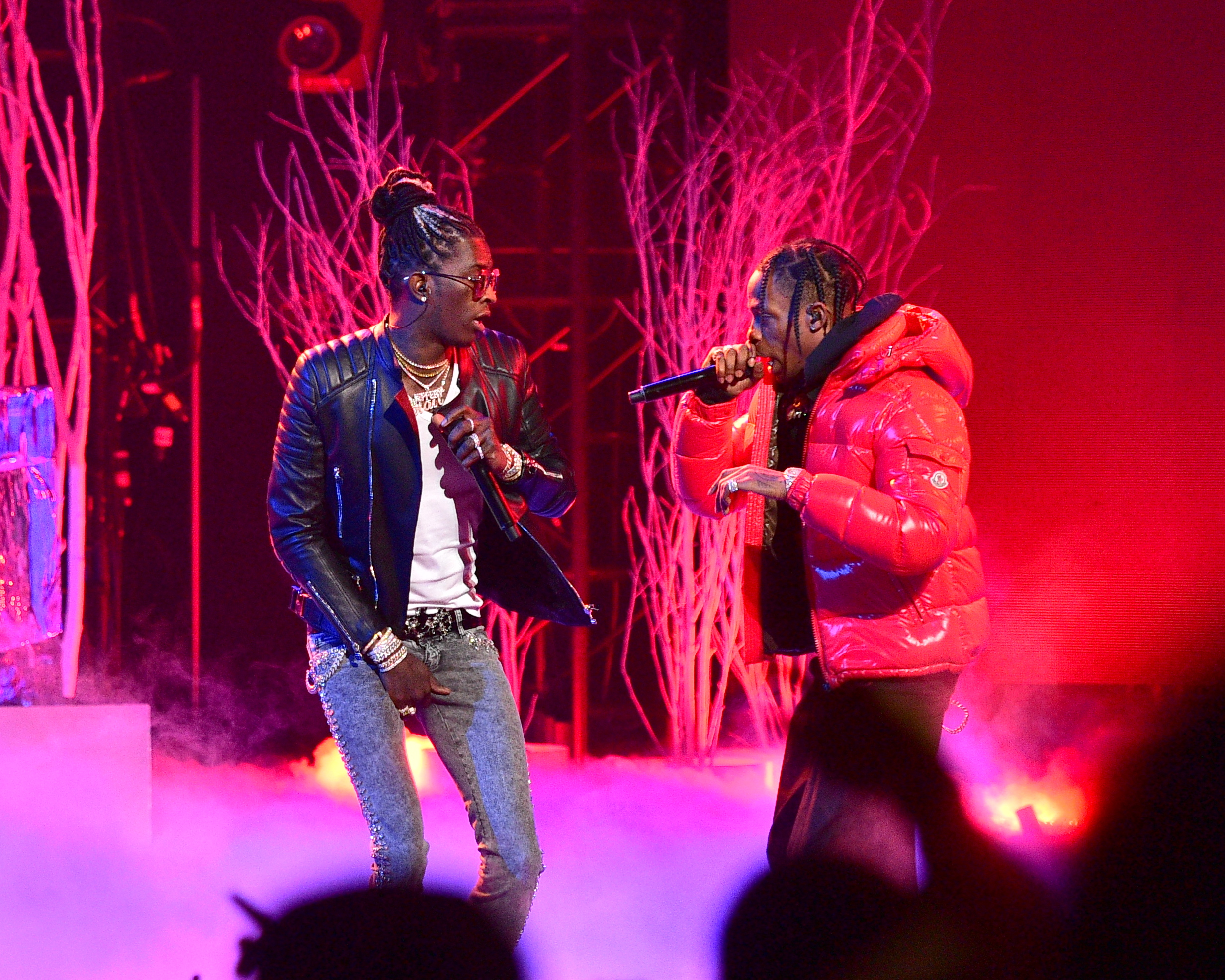 Young Thug, wearing a black leather jacket, performs alongside Travis Scott, who is dressed in a red Moncler coat. Both rappers had major songs in 2016, including their collaboration “Pick Up the Phone.”