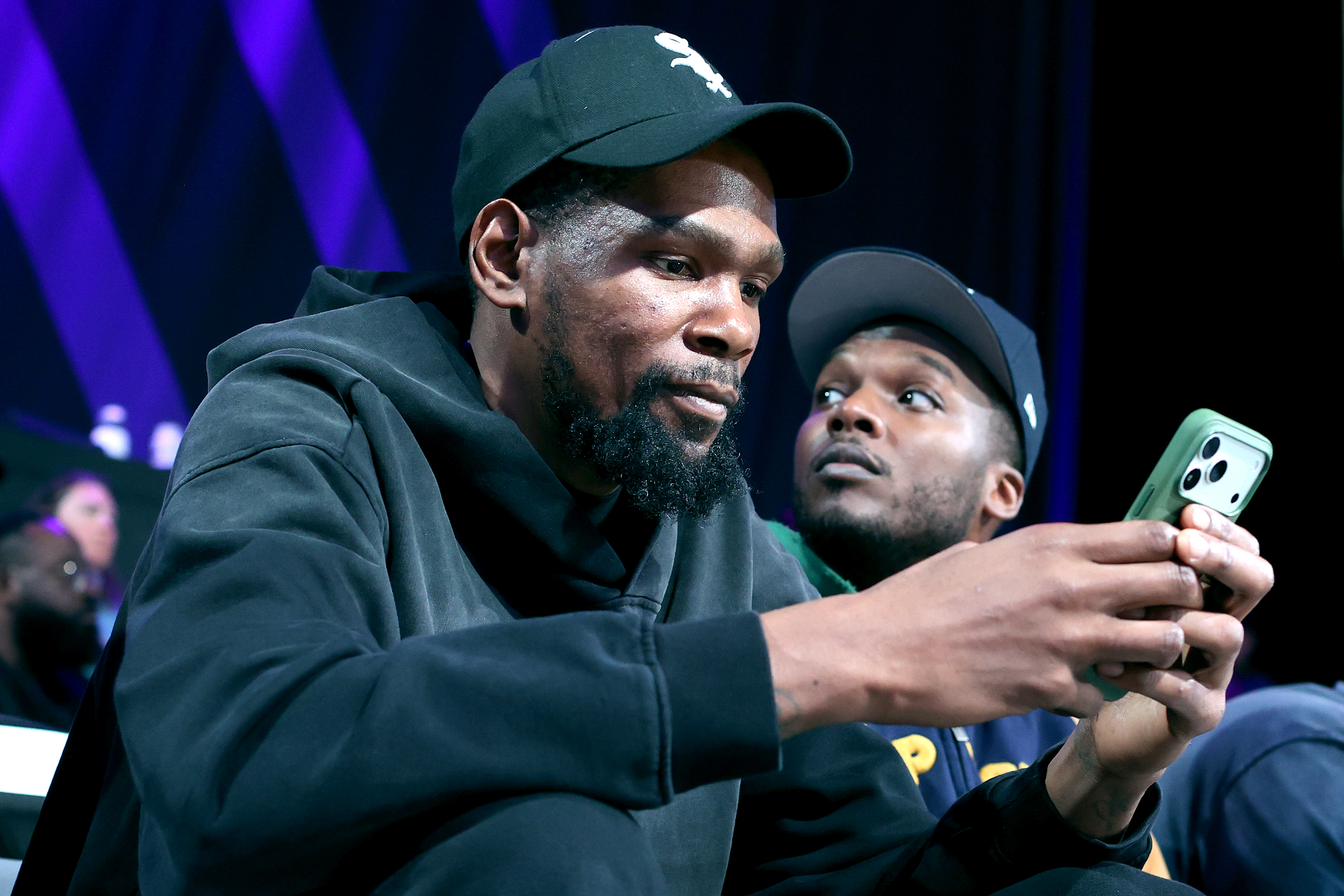 Kevin Durant looks at his phone while sitting courtside at an Unrivaled game in February 2026. 