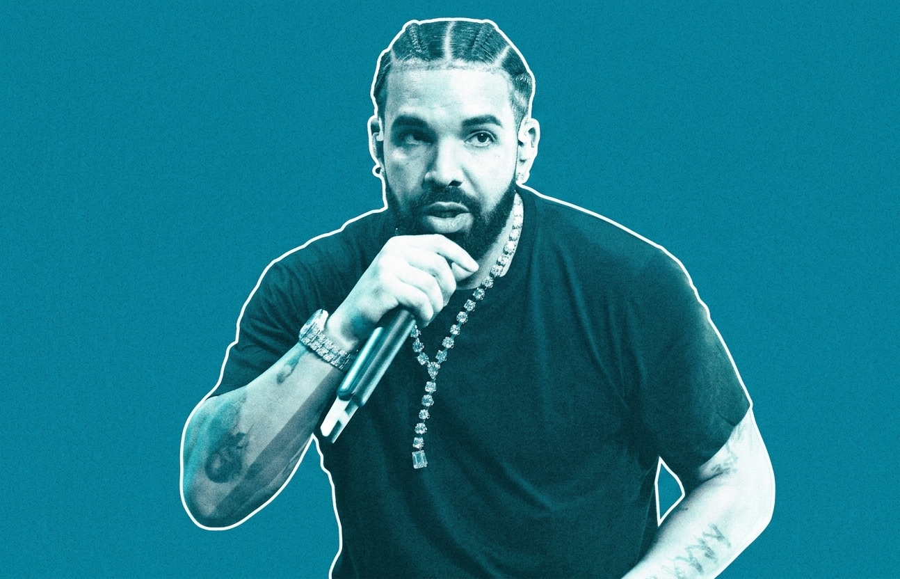 Drake performing, wearing a black shirt and a diamond necklace, holding a microphone against a blue background.