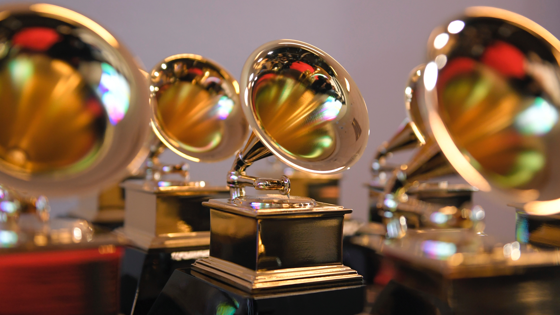 Close-up of multiple Grammy Award trophies, featuring gold gramophones on black bases, arranged in rows.