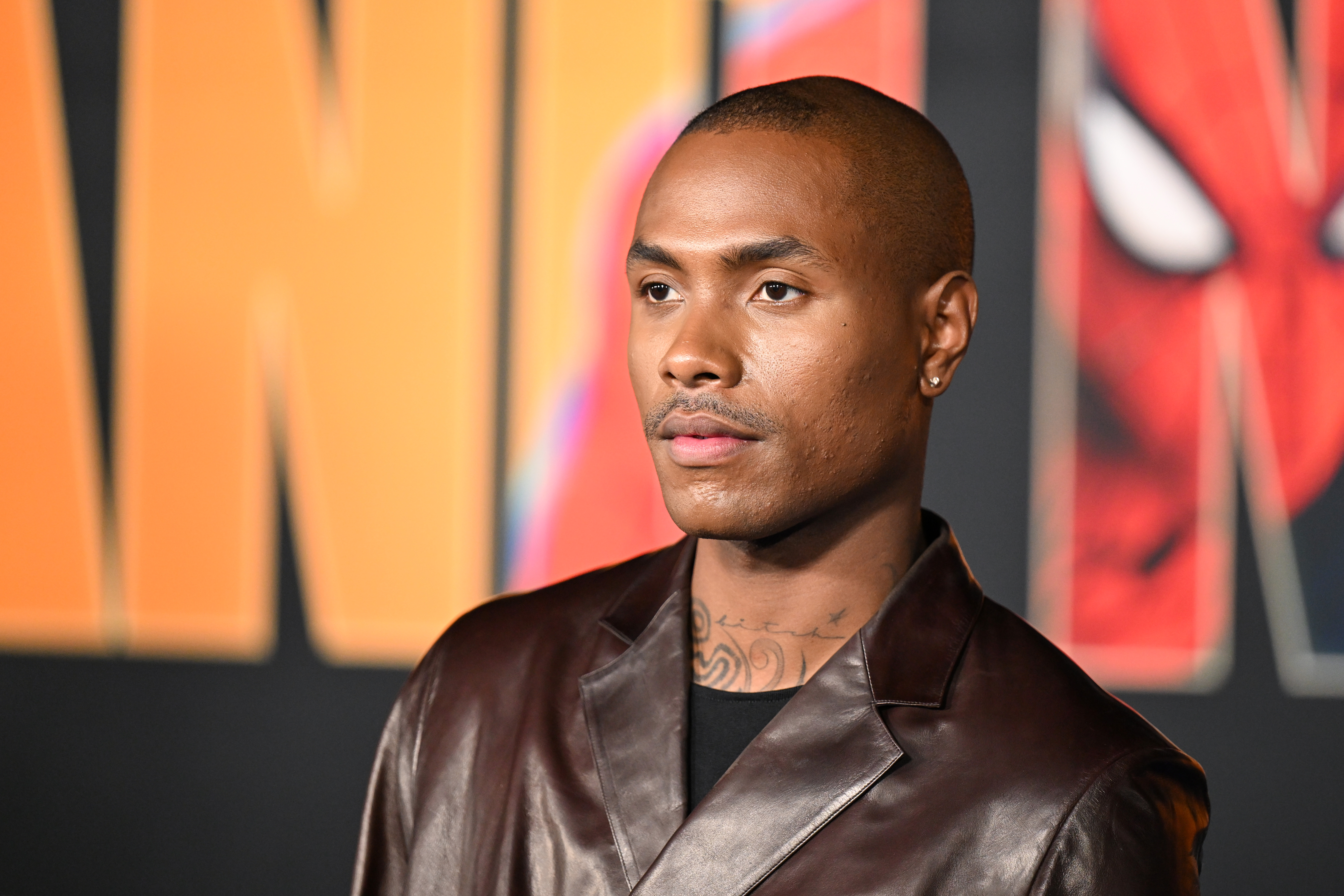 A person in a brown leather jacket stands in front of a colorful background with large text.